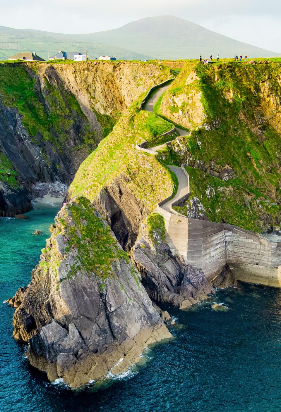 Dunquin or Dun Chaoin pier, Ireland's Sheep Highway. Aerial view of narrow pathway winding down to the pier, ocean coastline, cliffs. Popular location on Slea Head Drive and Wild Atlantic Way.